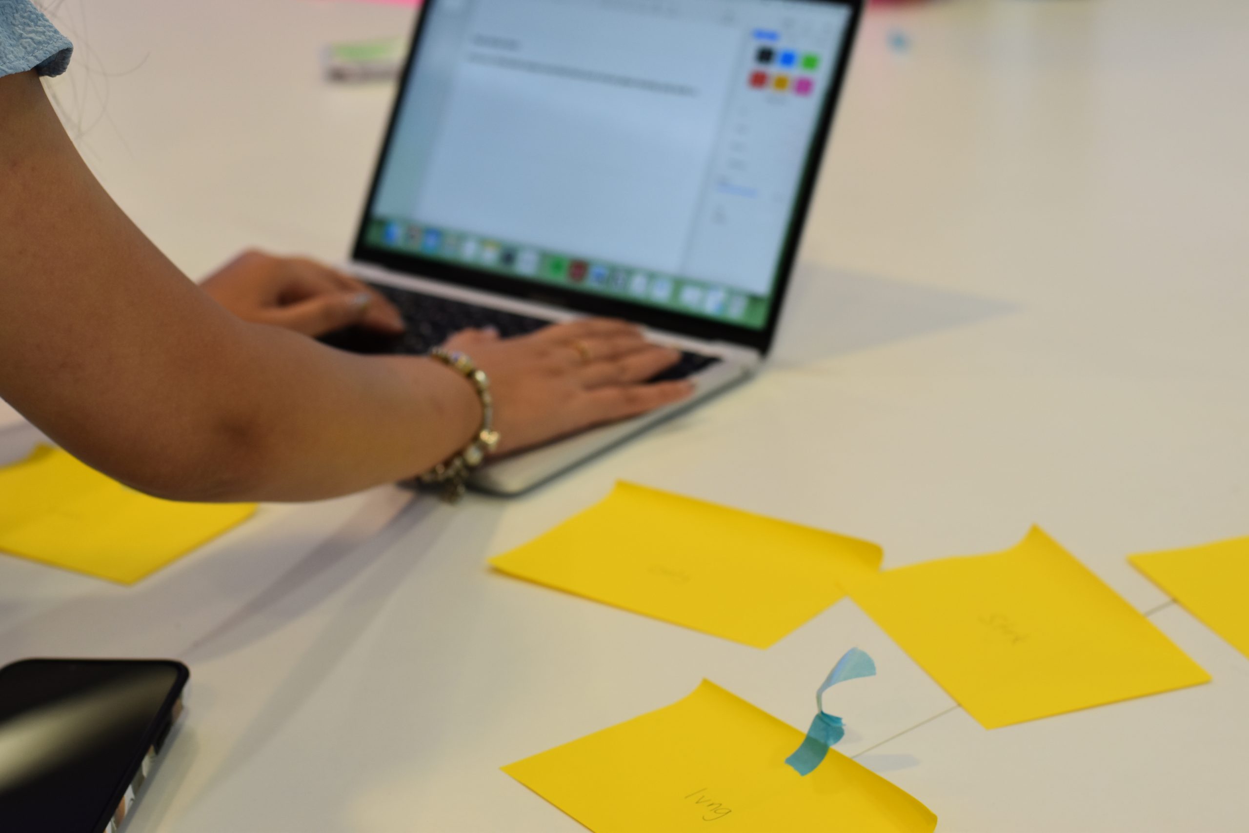 a lady typing on her laptop with post-its lying around her table