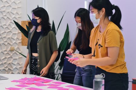 3 interpreters standing and looking at the pink post-its filled with messages