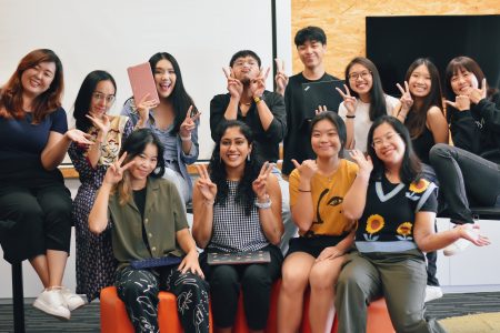 12 interpreters posing as a team some with victory signs and some holding their keyboard depicting their part of job